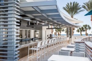 A bar with white chairs near an ocean