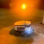 A small robotic courier with a yellow light