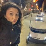A woman taking a selfie next to a car